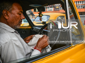 A taxi driver sits inside his yellow taxi, waiting for customers near Sealdah railway station in Kolkata, India. (