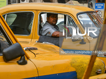 A taxi driver sits inside his yellow taxi, waiting for customers near Sealdah railway station in Kolkata, India. (