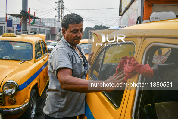 A taxi driver cleans his yellow taxi near Sealdah railway station in Kolkata, India. 