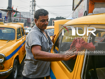 A taxi driver cleans his yellow taxi near Sealdah railway station in Kolkata, India. (