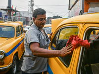 A taxi driver cleans his yellow taxi near Sealdah railway station in Kolkata, India. (