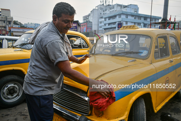 A taxi driver cleans his yellow taxi near Sealdah railway station in Kolkata, India. 