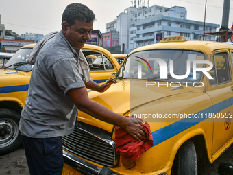 A taxi driver cleans his yellow taxi near Sealdah railway station in Kolkata, India. (