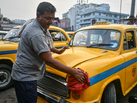 A taxi driver cleans his yellow taxi near Sealdah railway station in Kolkata, India. (