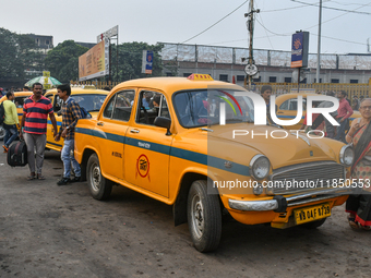 Passengers walk past a yellow taxi near Sealdah railway station in Kolkata. (