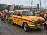 Passengers walk past a yellow taxi near Sealdah railway station in Kolkata. (