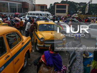 Passengers walk past yellow taxis near Sealdah railway station in Kolkata. (