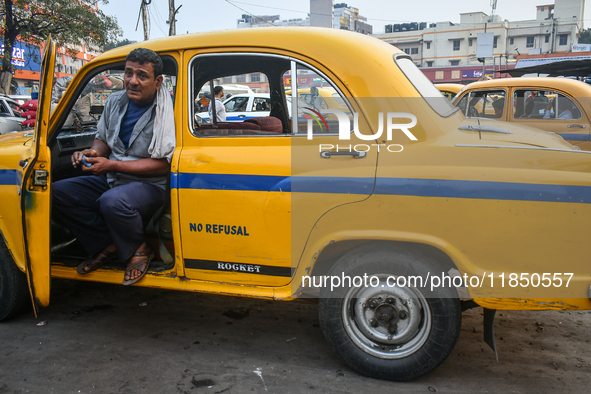 A taxi driver sits inside his yellow taxi, waiting for customers near Sealdah railway station in Kolkata, India. 