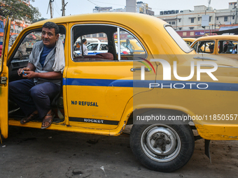 A taxi driver sits inside his yellow taxi, waiting for customers near Sealdah railway station in Kolkata, India. (