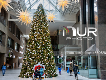 People pose for a selfie by a large Christmas tree decorated in Toronto, Ontario, Canada, on December 8, 2024. (