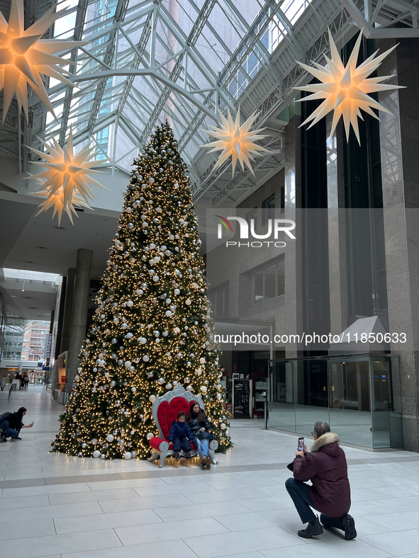 People pose for a photo by a large Christmas tree decorated in Toronto, Ontario, Canada, on December 8, 2024. 