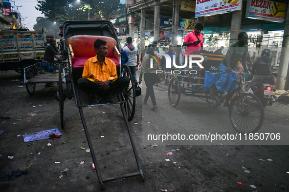 A hand-pulled rickshaw puller rests at the roadside in Kolkata. 