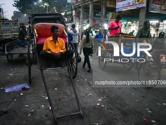 A hand-pulled rickshaw puller rests at the roadside in Kolkata. (