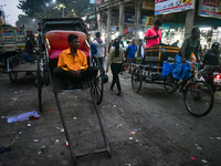 A hand-pulled rickshaw puller rests at the roadside in Kolkata. (