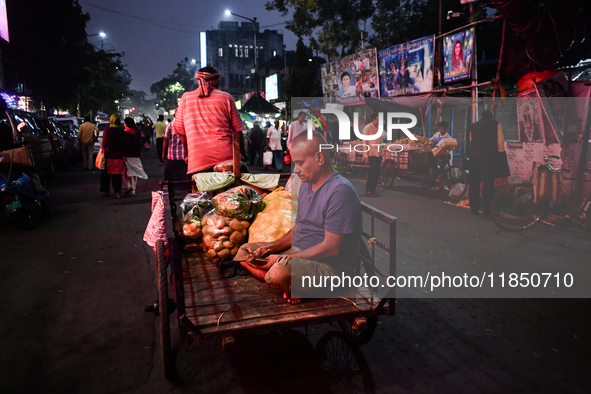 A vegetable seller counts money while his van driver pulls the van full of vegetables in Kolkata. 