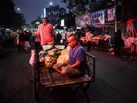 A vegetable seller counts money while his van driver pulls the van full of vegetables in Kolkata. (