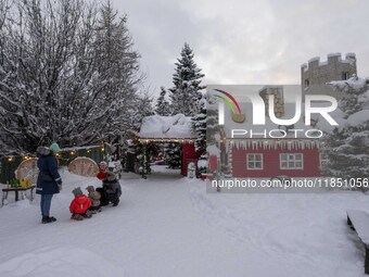 People interact at one of the entrances to a Christmas village in Akureyri, Iceland, on November 30, 2024. Christmas in Iceland, known as Jo...