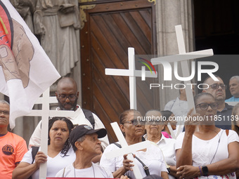 People hold crosses during a demonstration in downtown Sao Paulo, Brazil, on December 9, 2024, to protest against police violence following...