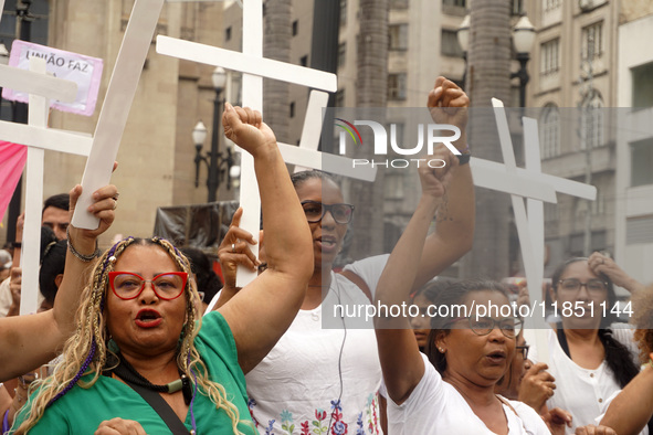 People hold crosses during a demonstration in downtown Sao Paulo, Brazil, on December 9, 2024, to protest against police violence following...