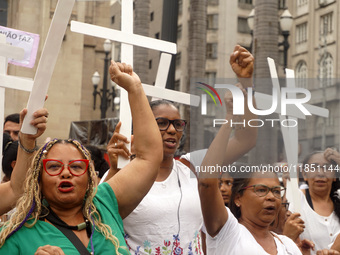 People hold crosses during a demonstration in downtown Sao Paulo, Brazil, on December 9, 2024, to protest against police violence following...