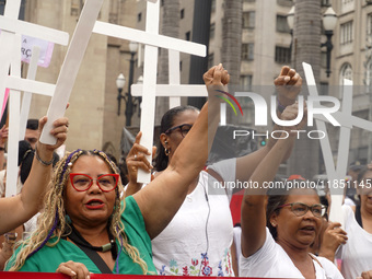 People hold crosses during a demonstration in downtown Sao Paulo, Brazil, on December 9, 2024, to protest against police violence following...