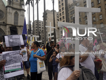 People hold crosses during a demonstration in downtown Sao Paulo, Brazil, on December 9, 2024, to protest against police violence following...