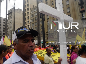 People hold crosses during a demonstration in downtown Sao Paulo, Brazil, on December 9, 2024, to protest against police violence following...