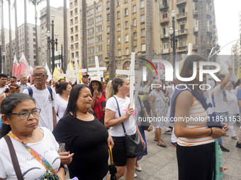 People hold crosses during a demonstration in downtown Sao Paulo, Brazil, on December 9, 2024, to protest against police violence following...