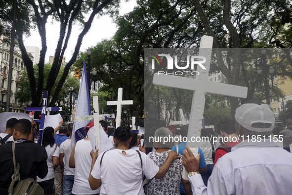 People hold crosses during a demonstration in downtown Sao Paulo, Brazil, on December 9, 2024, to protest against police violence following...