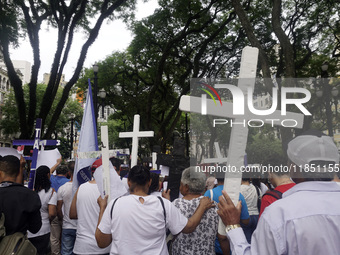 People hold crosses during a demonstration in downtown Sao Paulo, Brazil, on December 9, 2024, to protest against police violence following...