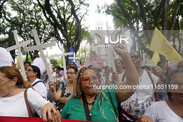 People hold crosses during a demonstration in downtown Sao Paulo, Brazil, on December 9, 2024, to protest against police violence following...