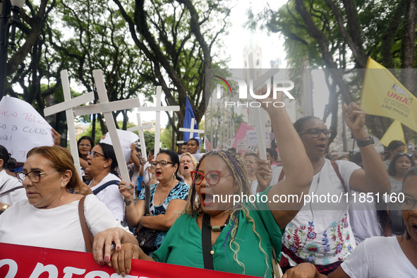 People hold crosses during a demonstration in downtown Sao Paulo, Brazil, on December 9, 2024, to protest against police violence following...