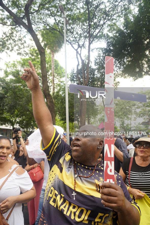 People hold crosses during a demonstration in downtown Sao Paulo, Brazil, on December 9, 2024, to protest against police violence following...