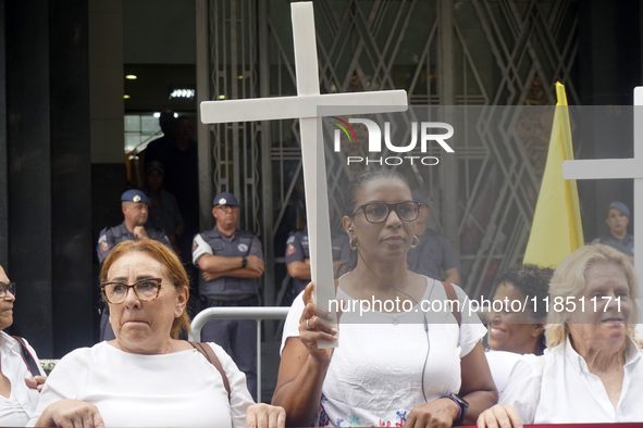 People hold crosses during a demonstration in downtown Sao Paulo, Brazil, on December 9, 2024, to protest against police violence following...