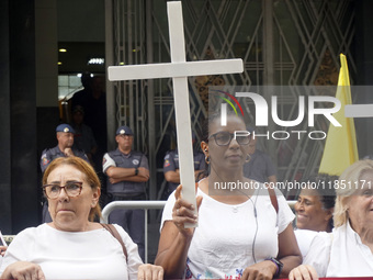 People hold crosses during a demonstration in downtown Sao Paulo, Brazil, on December 9, 2024, to protest against police violence following...