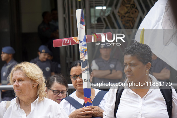 People hold crosses during a demonstration in downtown Sao Paulo, Brazil, on December 9, 2024, to protest against police violence following...