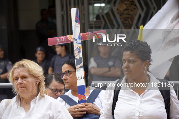 People hold crosses during a demonstration in downtown Sao Paulo, Brazil, on December 9, 2024, to protest against police violence following...