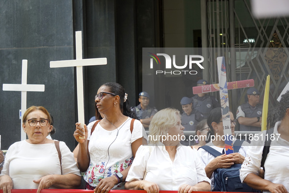 People hold crosses during a demonstration in downtown Sao Paulo, Brazil, on December 9, 2024, to protest against police violence following...