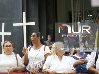 People hold crosses during a demonstration in downtown Sao Paulo, Brazil, on December 9, 2024, to protest against police violence following...