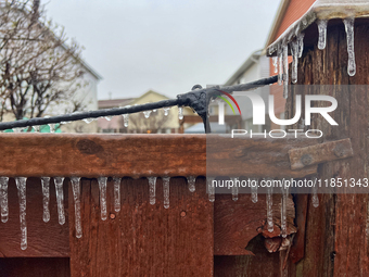 Icicles hang from a wooden fence as freezing rain coats surfaces with a sheet of ice in Toronto, Ontario, Canada, on December 9, 2024. (