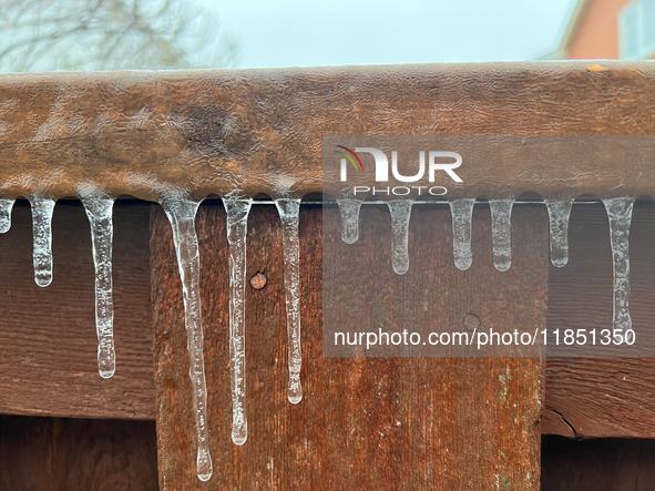 Icicles hang from a wooden fence as freezing rain coats surfaces with a sheet of ice in Toronto, Ontario, Canada, on December 9, 2024. 