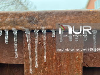 Icicles hang from a wooden fence as freezing rain coats surfaces with a sheet of ice in Toronto, Ontario, Canada, on December 9, 2024. (