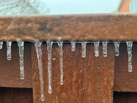 Icicles hang from a wooden fence as freezing rain coats surfaces with a sheet of ice in Toronto, Ontario, Canada, on December 9, 2024. (