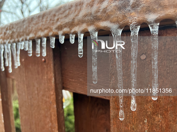 Icicles hang from a wooden fence as freezing rain coats surfaces with a sheet of ice in Toronto, Ontario, Canada, on December 9, 2024. 