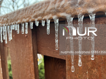 Icicles hang from a wooden fence as freezing rain coats surfaces with a sheet of ice in Toronto, Ontario, Canada, on December 9, 2024. (