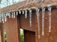 Icicles hang from a wooden fence as freezing rain coats surfaces with a sheet of ice in Toronto, Ontario, Canada, on December 9, 2024. (