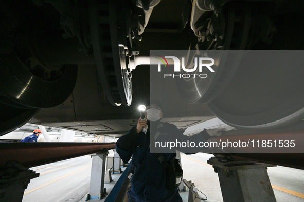 A ground service mechanic inspects a bullet train at the maintenance garage of the Nanjing South Bullet Train service station in Nanjing, Ji...