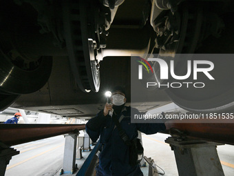 A ground service mechanic inspects a bullet train at the maintenance garage of the Nanjing South Bullet Train service station in Nanjing, Ji...