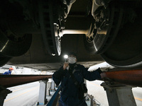 A ground service mechanic inspects a bullet train at the maintenance garage of the Nanjing South Bullet Train service station in Nanjing, Ji...