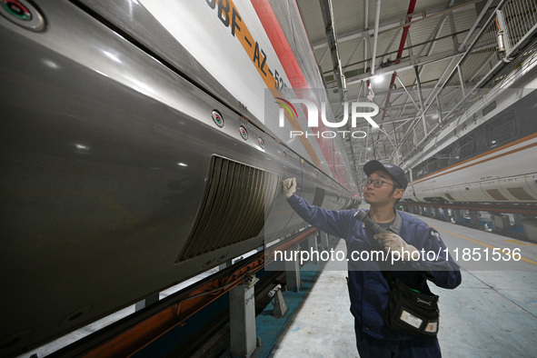 A ground service mechanic inspects a bullet train at the maintenance garage of the Nanjing South Bullet Train service station in Nanjing, Ji...